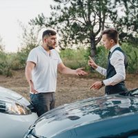 two Young Man Arguing With Each Other After Car Accident On Street At Outdoors.