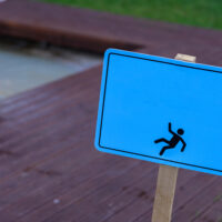 Wet floor warning sign near swimming pool